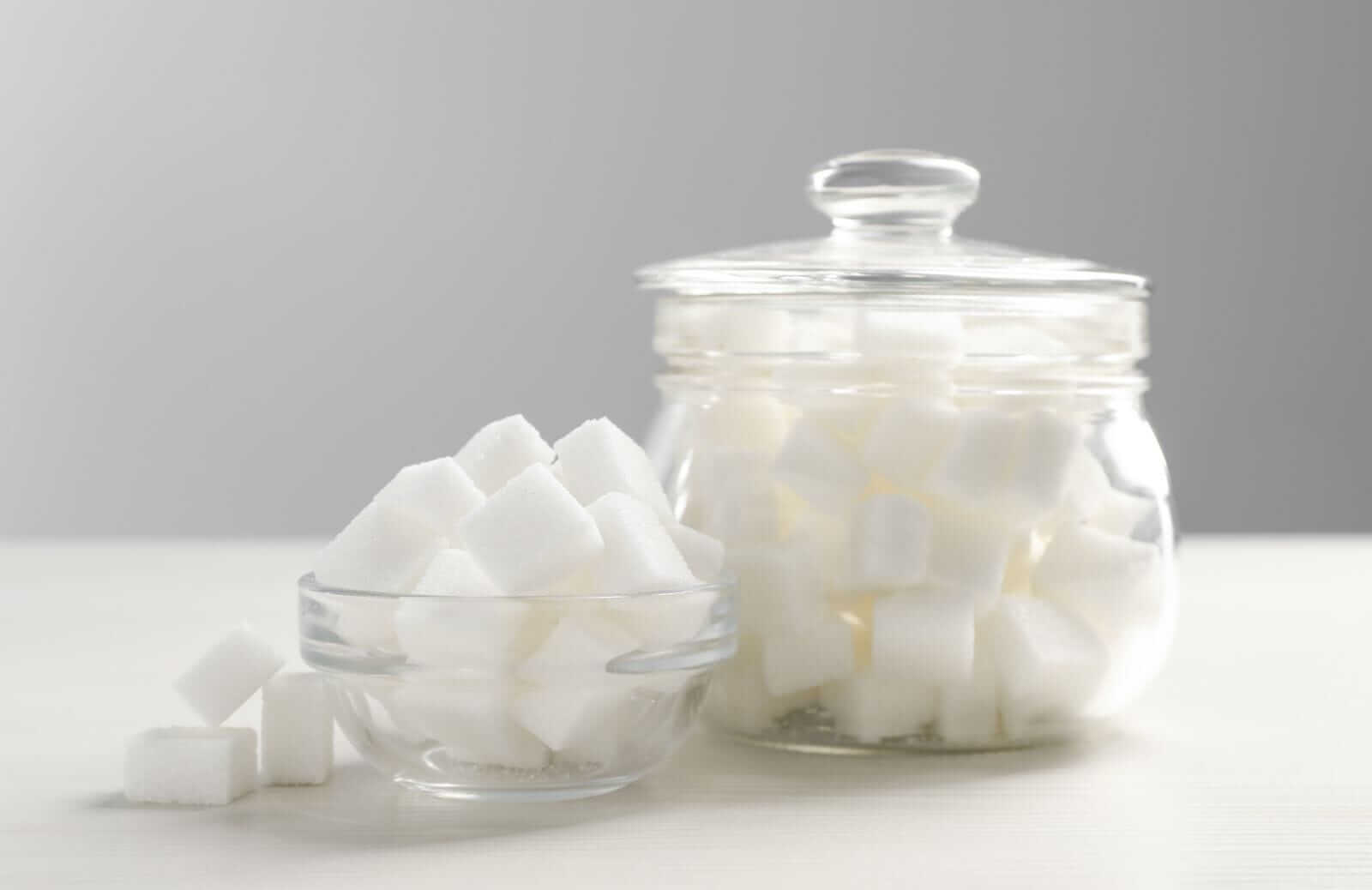 Glass jar and bowl with white sugar cubes on table by Liudmila Chernetska via iStock